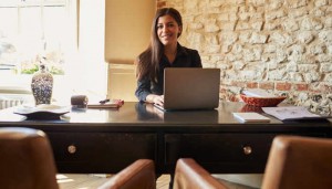 Young woman at the check-in desk of a hotel looks to camera