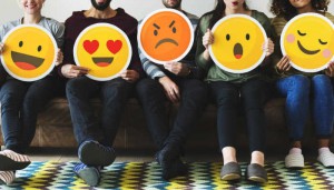 Group of diverse people holding emoticon icons