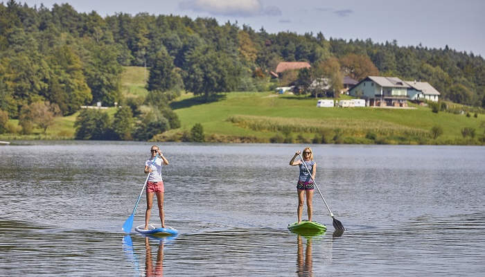 The two females riding a stand up paddle board in the Smartinsko lake in Slovenia