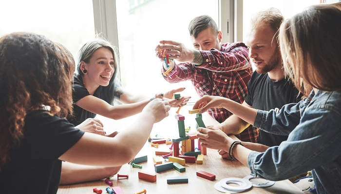 A group of creative friends sitting on a wooden table. People were having fun while playing a board game