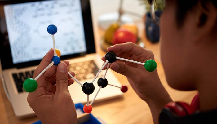 Close-up image of chemical element model in hands on student