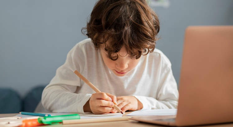 Niño dando clases online con el ordenador. 