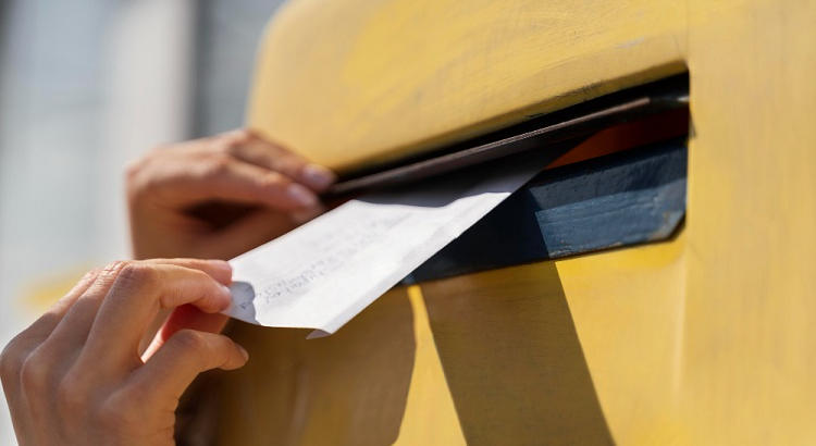 Persona introduciendo una carta en un buzón de Correos. 