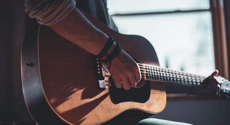 Joven adolescente tocando la guitarra. | Foto de Jacek Dylag vía Unsplash